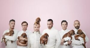 Rammstein-Mitglieder mit je einem Hund auf dem Arm. Tour Banner 2021