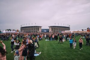 Ein Foto vom Lollapalooza Berlin 2022. Zu erkennen sind eine große Menschenmenge auf dem Maifeld, im Hintergrund das Olympiastadion Berlin