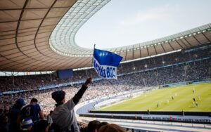 Ein Fan von Hertha BSC schwenkt eine Fahne im vollen Olympiastadion Berlin