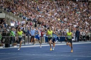 Läufer beim Sprint auf der blauen Laufbahn im Olympiastadion Berlin.