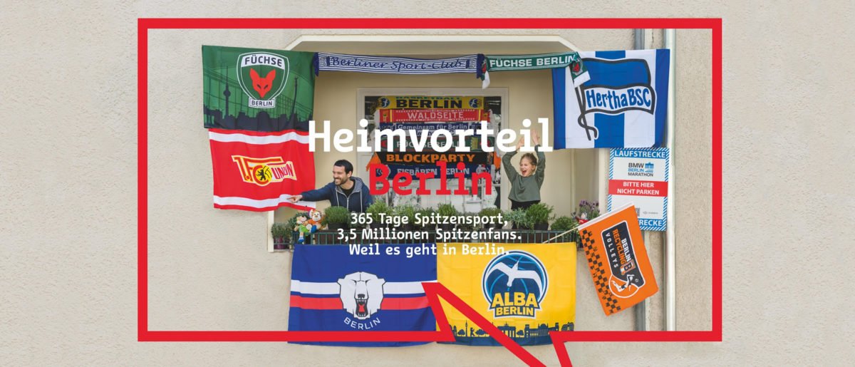 Kampagnenplakat „Heimvorteil Berlin“: Ein mit Flaggen zahlreicher Berliner Sportvereine (u. a. Hertha BSC, Union Berlin, ALBA, Eisbären, Füchse) dekorierter Balkon mit zwei jubelnden Fans, umrahmt von einer großen roten Sprechblase.